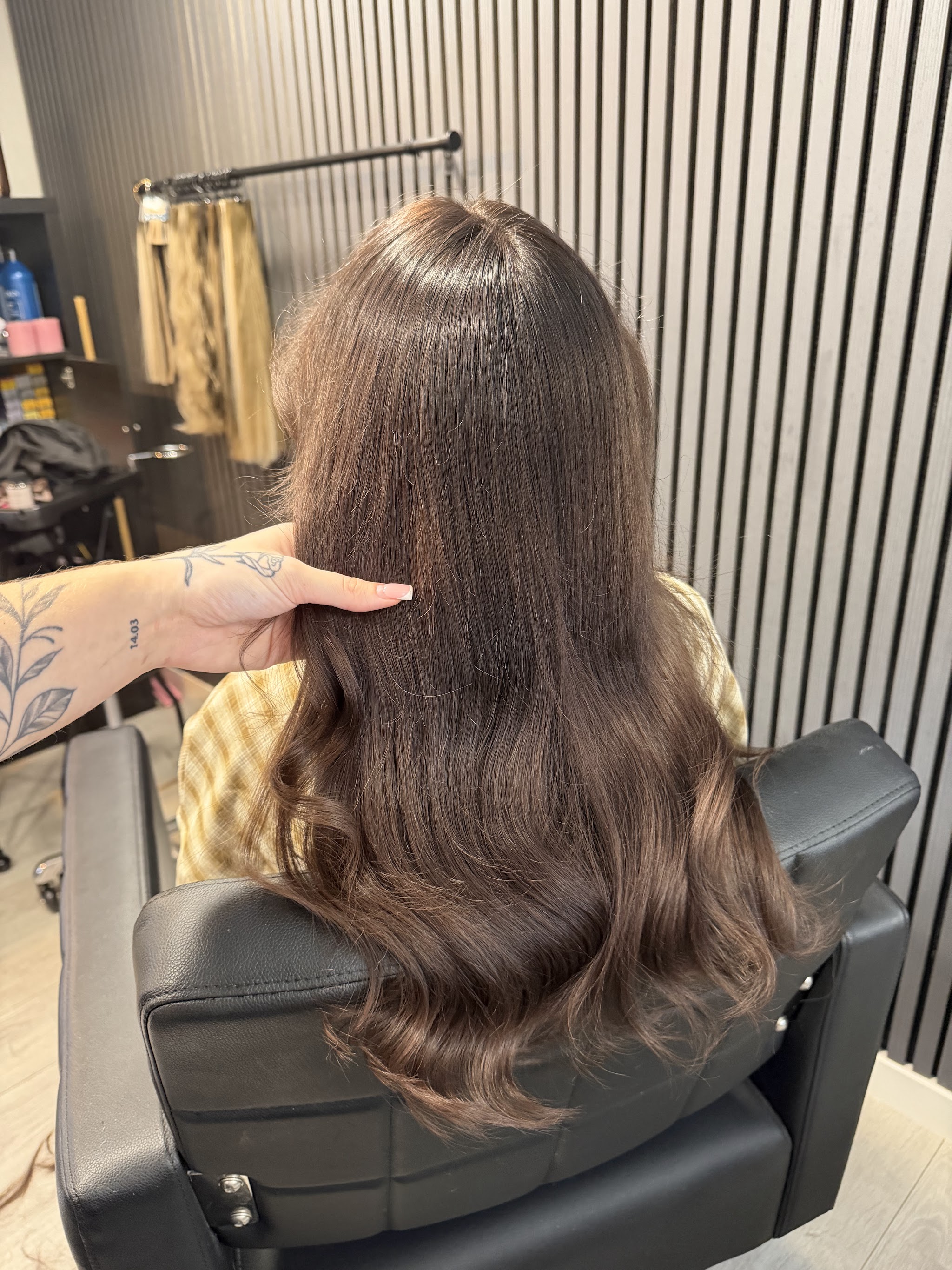 Lang donkerbruin haar met slagen in de salonstoel, extensions aan het rek op de achtergrond