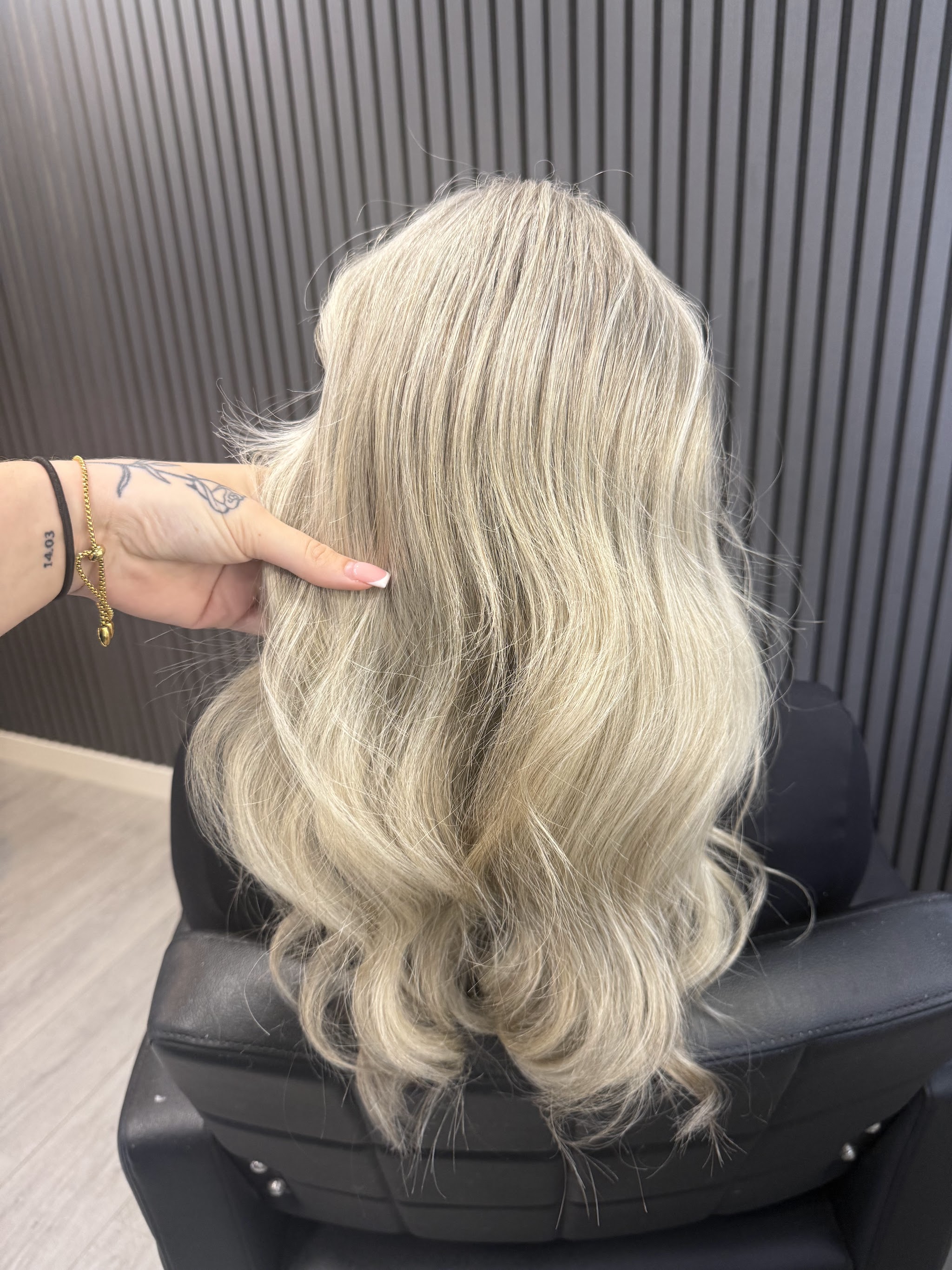 Lange asblonde golven in de stoel bij May Blonde, voor de zwarte latjeswand
