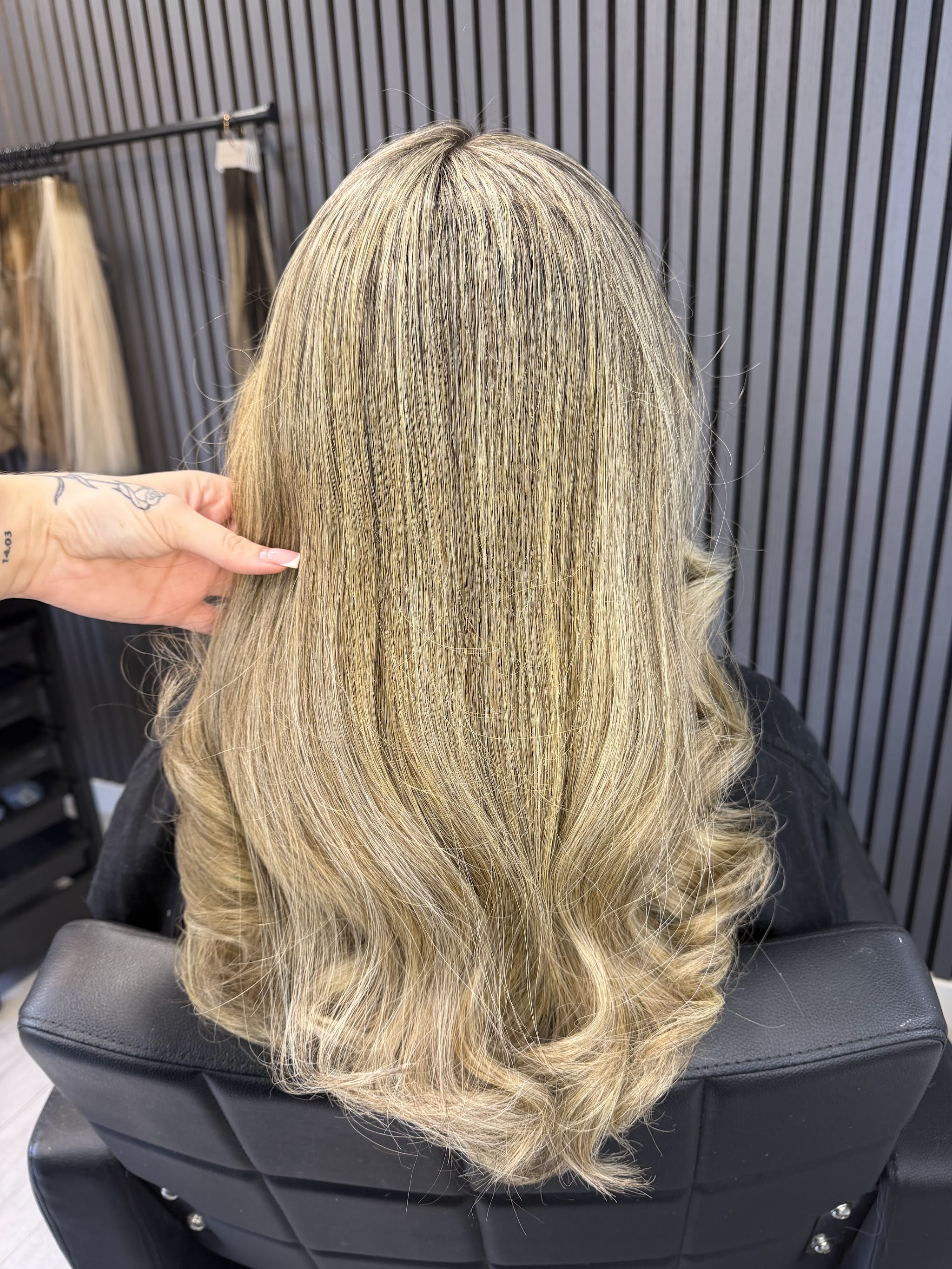 Lang beigeblond haar met highlights in de stoel voor de latjeswand