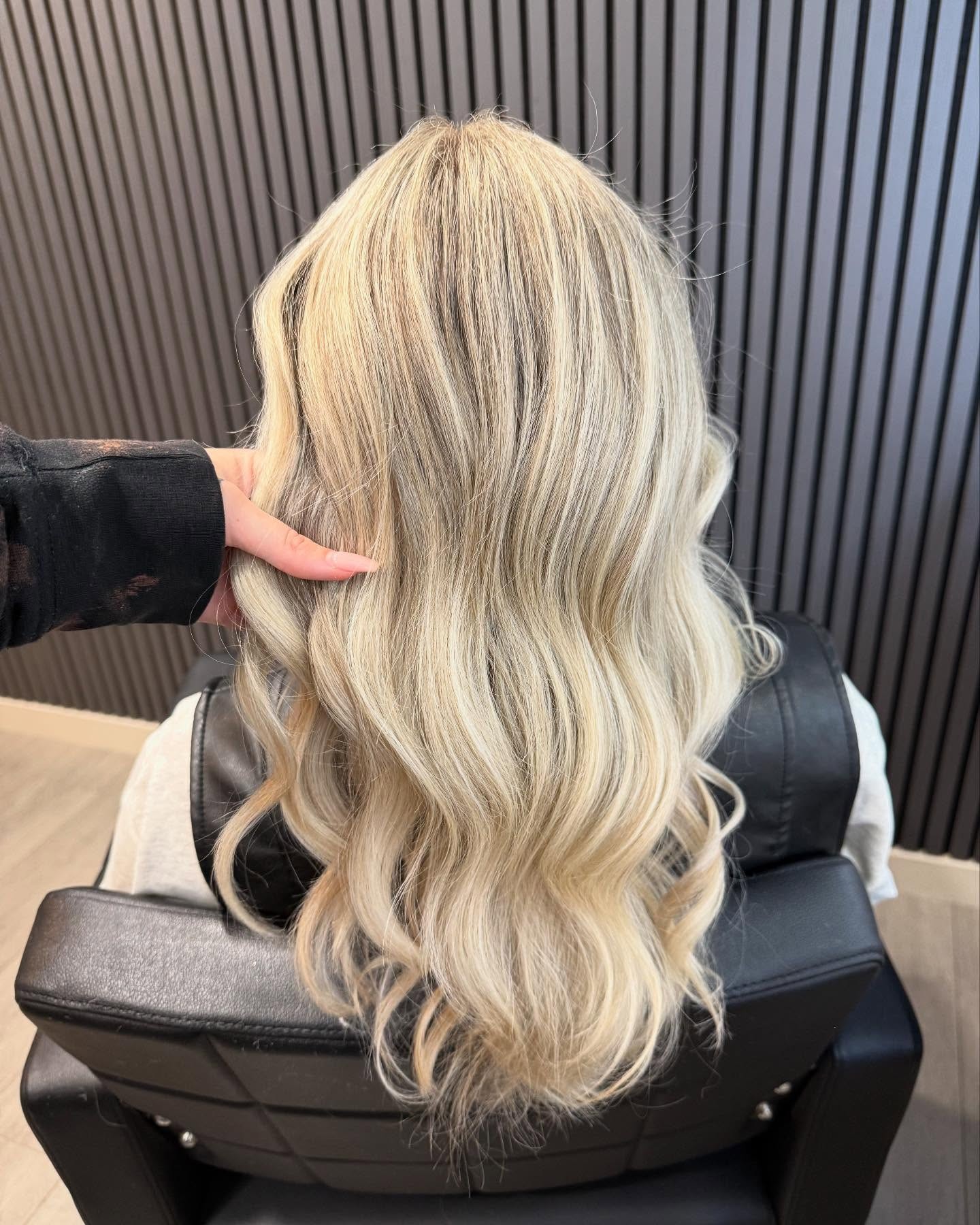 Blond haar met zachte golven in de stoel voor de latjeswand