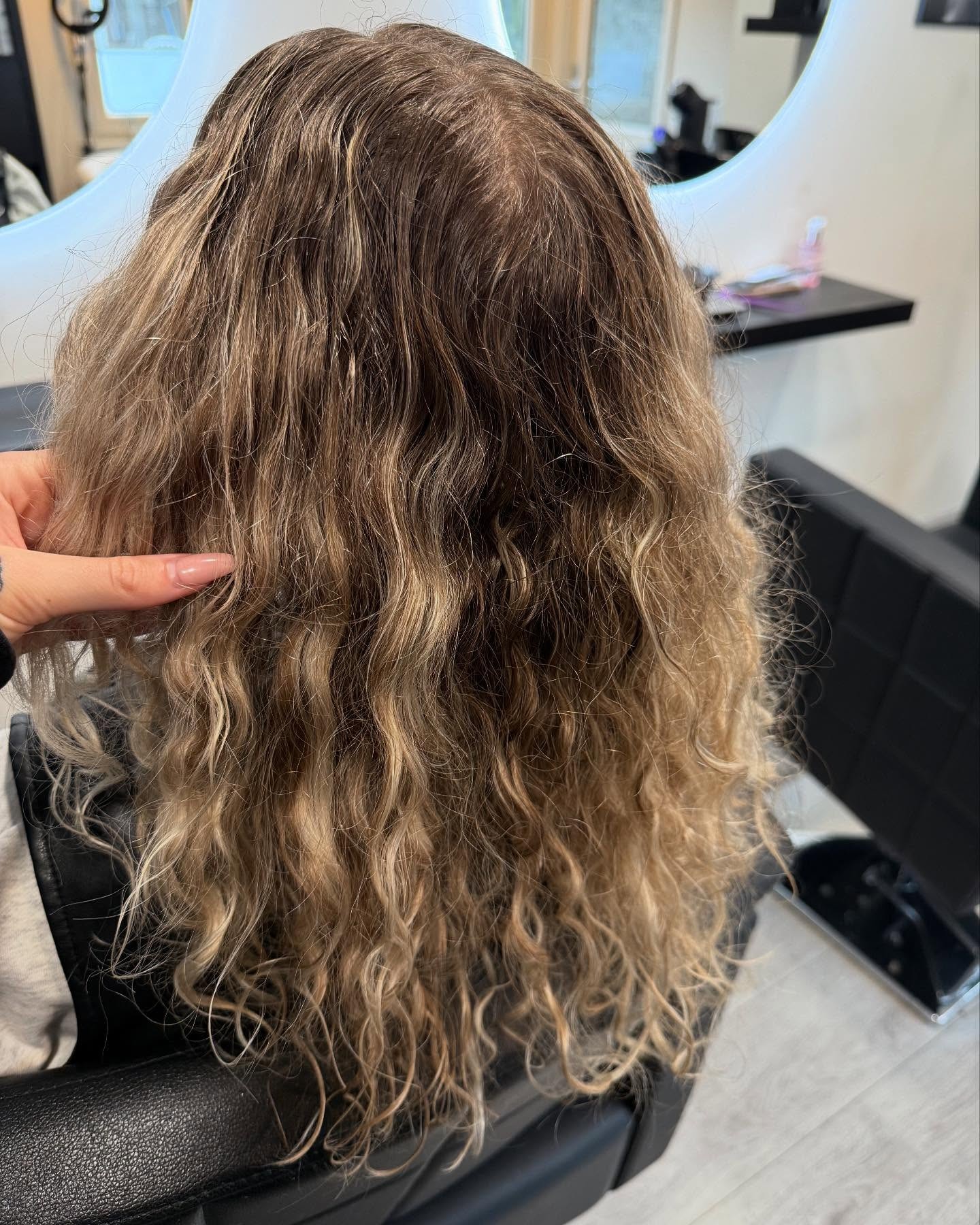 Krullend bruinblond haar in de stoel bij de ronde spiegel